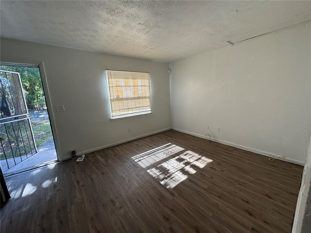 An empty room with wood-look flooring, white walls, a window with blinds, and an exterior door — 1131 PHELPS STREET, JACKSONVILLE, FL