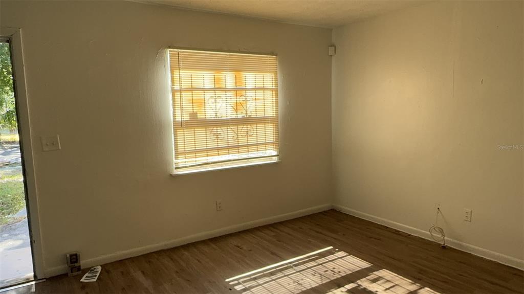 An empty room features light-colored walls, wood-look flooring, and a window with closed blinds — 1131 PHELPS STREET, JACKSONVILLE, FL