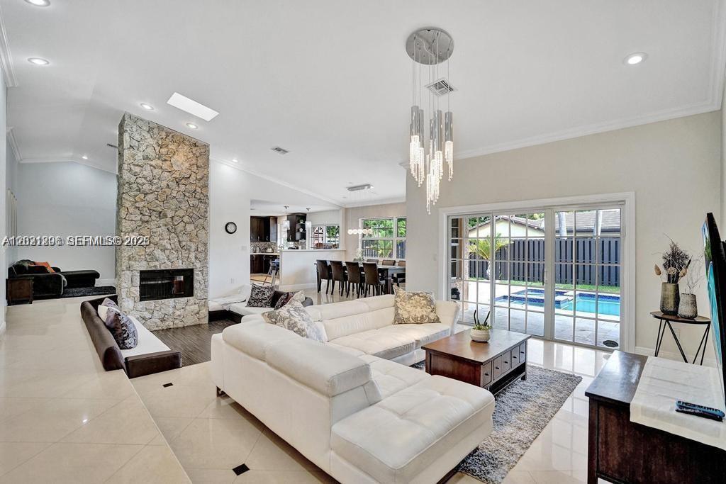 A spacious living room features a stone fireplace, white sectional sofa, and a pool view — 2001 NE 214th St, Miami FL 33179, MIAMI, FL