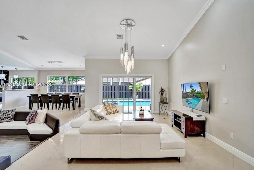 A living room with a white sectional sofa, a wall-mounted television, and a pool view — 2001 NE 214th St, Miami FL 33179, MIAMI, FL