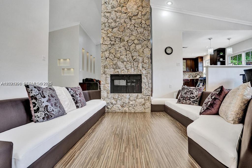 A living room features a stone fireplace, wood-look flooring, and two large sectional sofas — 2001 NE 214th St, Miami FL 33179, MIAMI, FL