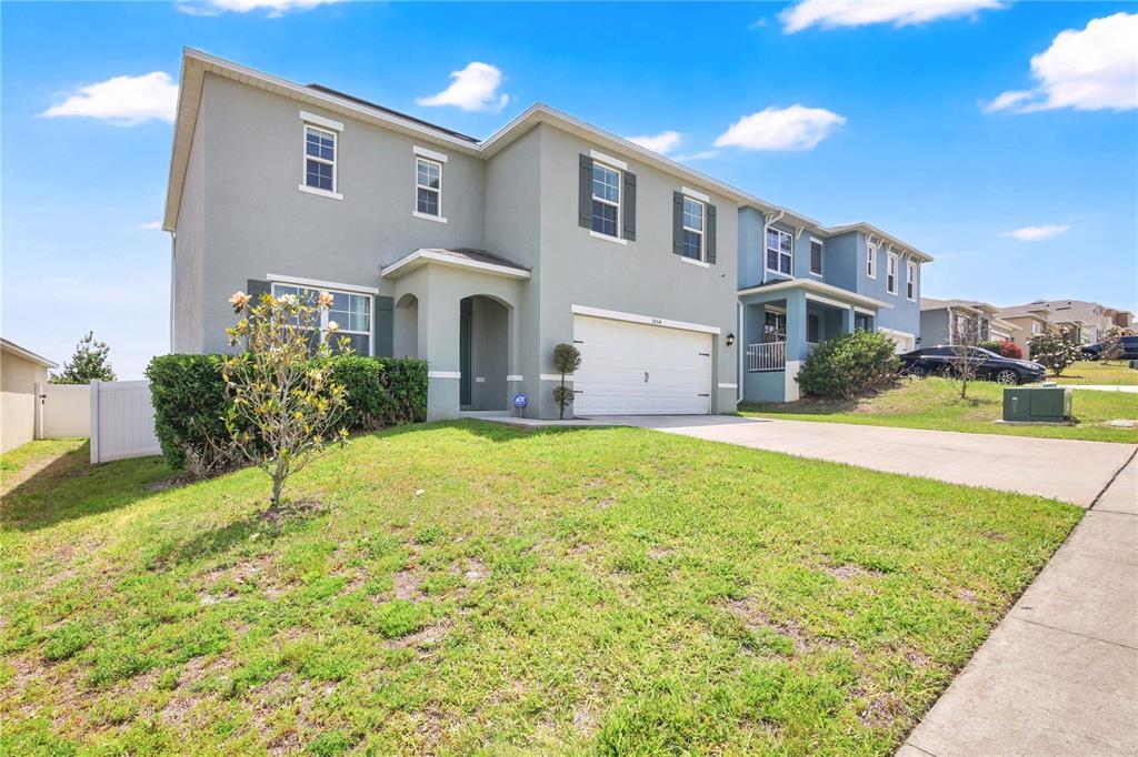 A two-story house with a gray stucco exterior, a two-car garage, and a front lawn — 1854 JUNEBERRY STREET, CLERMONT, FL