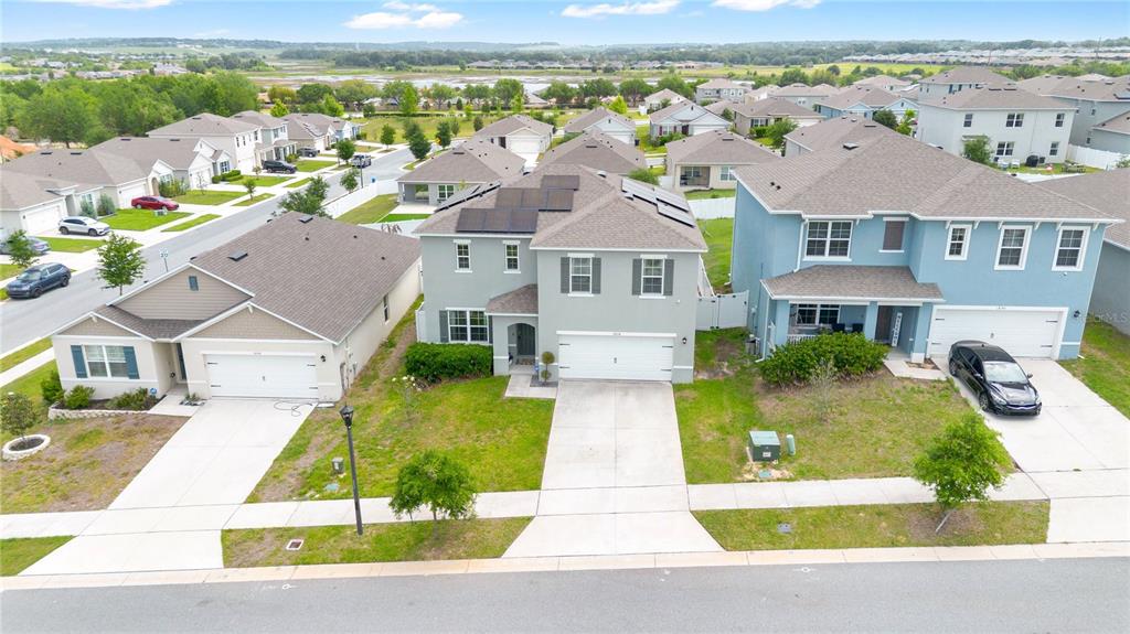 An aerial view shows three suburban houses with driveways and lawns in a residential neighborhood — 1854 JUNEBERRY STREET, CLERMONT, FL