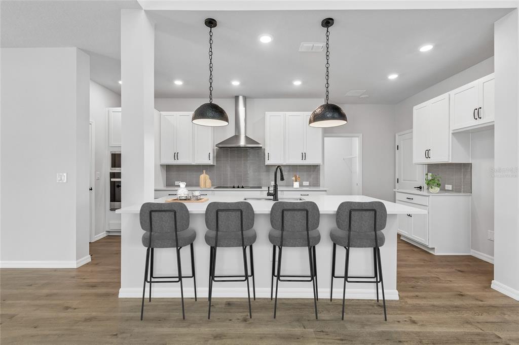 A kitchen with a green island, white countertops, stainless steel appliances, and light wood flooring — 626 KINGSWOOD COURT, BRADENTON, FL