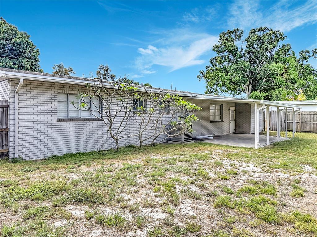 The exterior of a single-story brick house features a covered patio and a grassy yard — 4509 S HALE AVENUE, TAMPA, FL