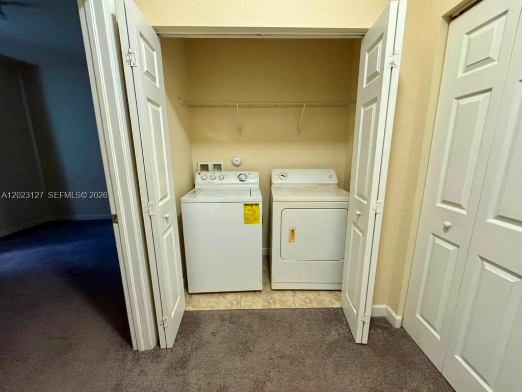 A laundry closet contains a white top-loading washer and a dryer with folding doors — HOMESTEAD, FL