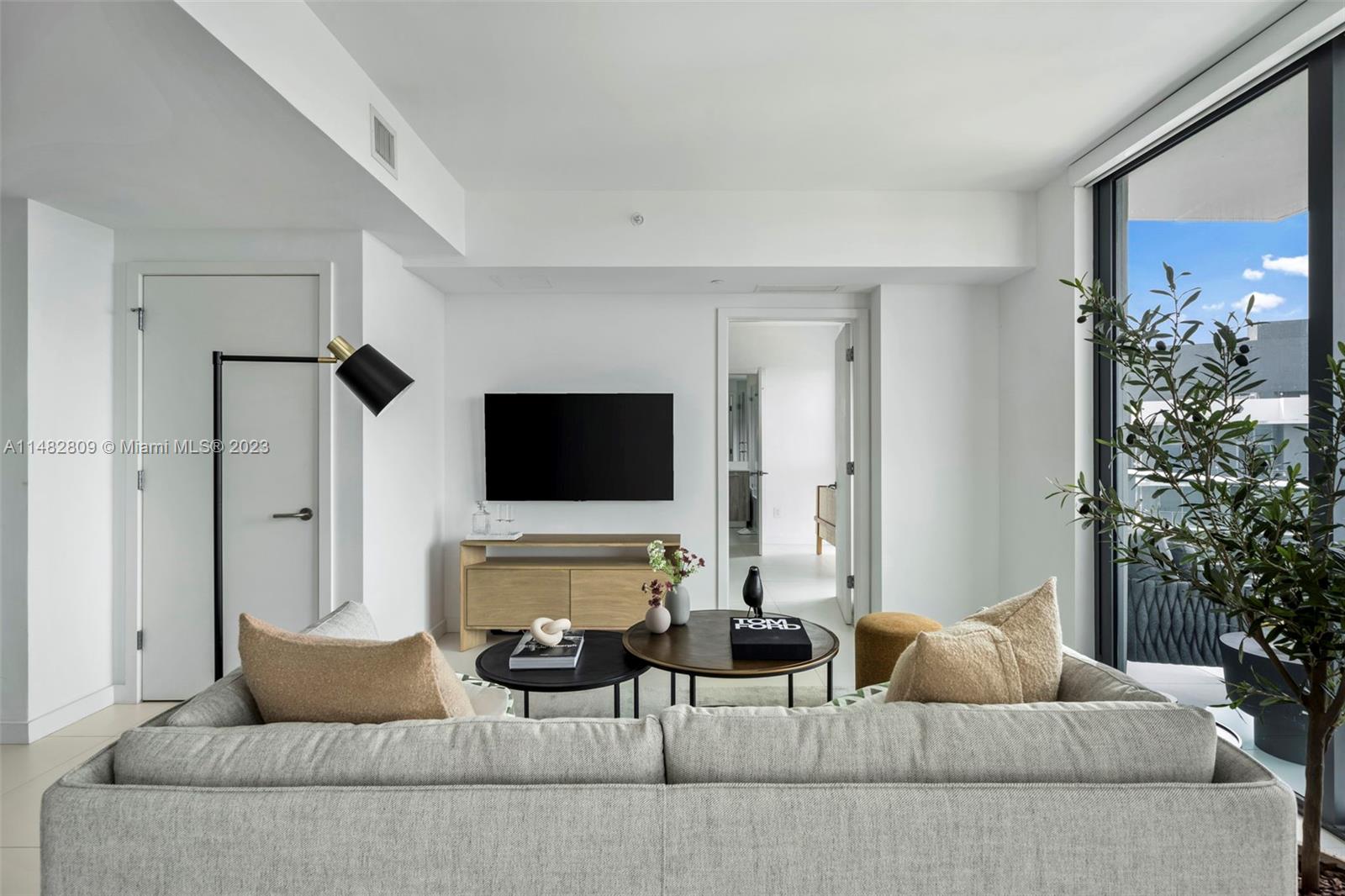 A modern living room features a grey sofa, two coffee tables, and a wall-mounted television — 501 NE 31st St # 3409, Miami FL 33137, MIAMI, FL