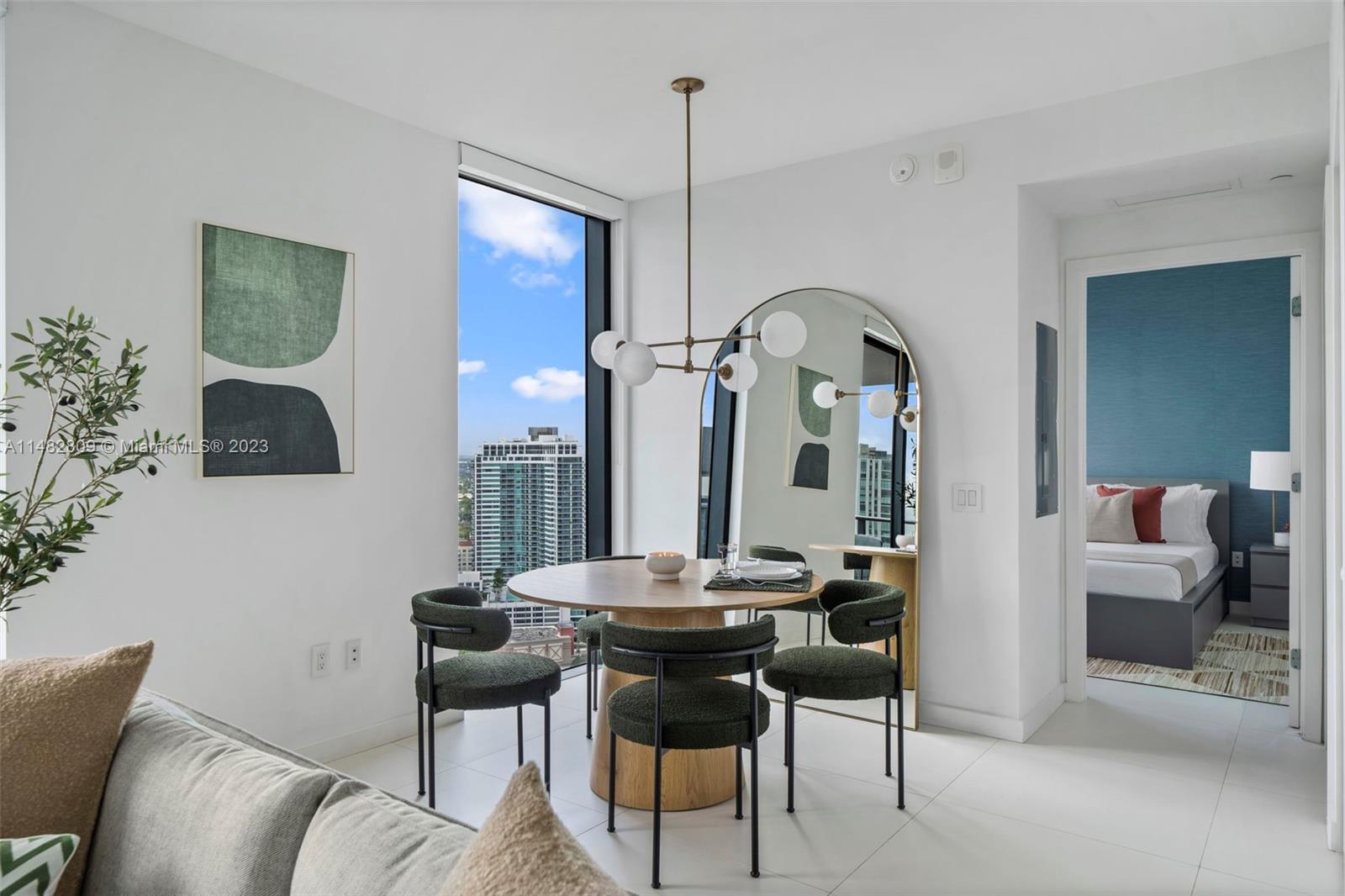 A dining area features a round wooden table, four green chairs, and a large arched mirror — 501 NE 31st St # 3409, Miami FL 33137, MIAMI, FL