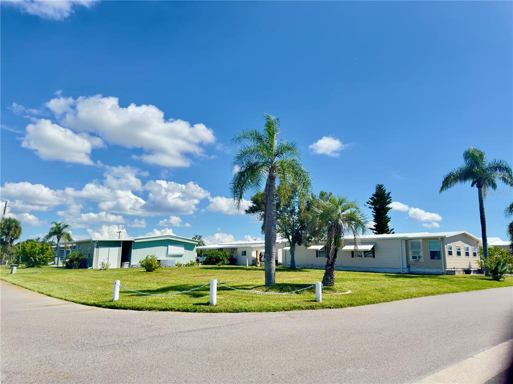 A view of two manufactured homes situated on a grassy corner lot with palm trees — 401 BLACKBURN BOULEVARD, NORTH PORT, FL