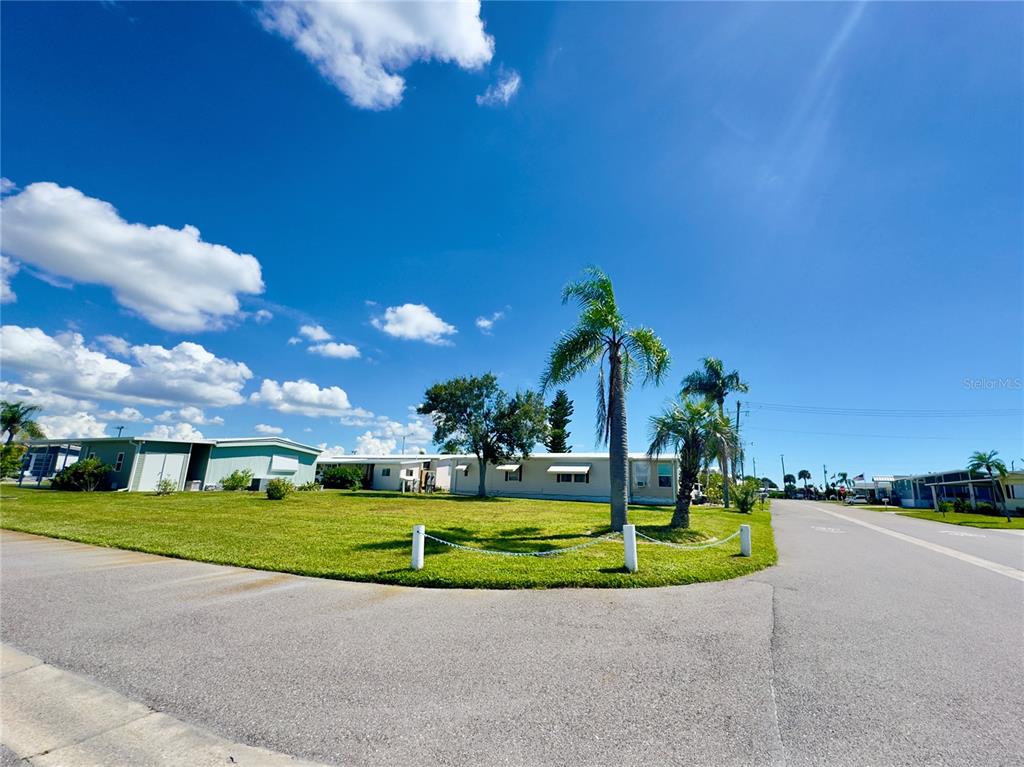 A single-story manufactured home sits on a grassy corner lot with palm trees — 401 BLACKBURN BOULEVARD, NORTH PORT, FL