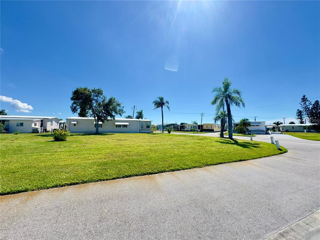 A grassy lot with palm trees and mobile homes under a bright blue sky — 401 BLACKBURN BOULEVARD, NORTH PORT, FL