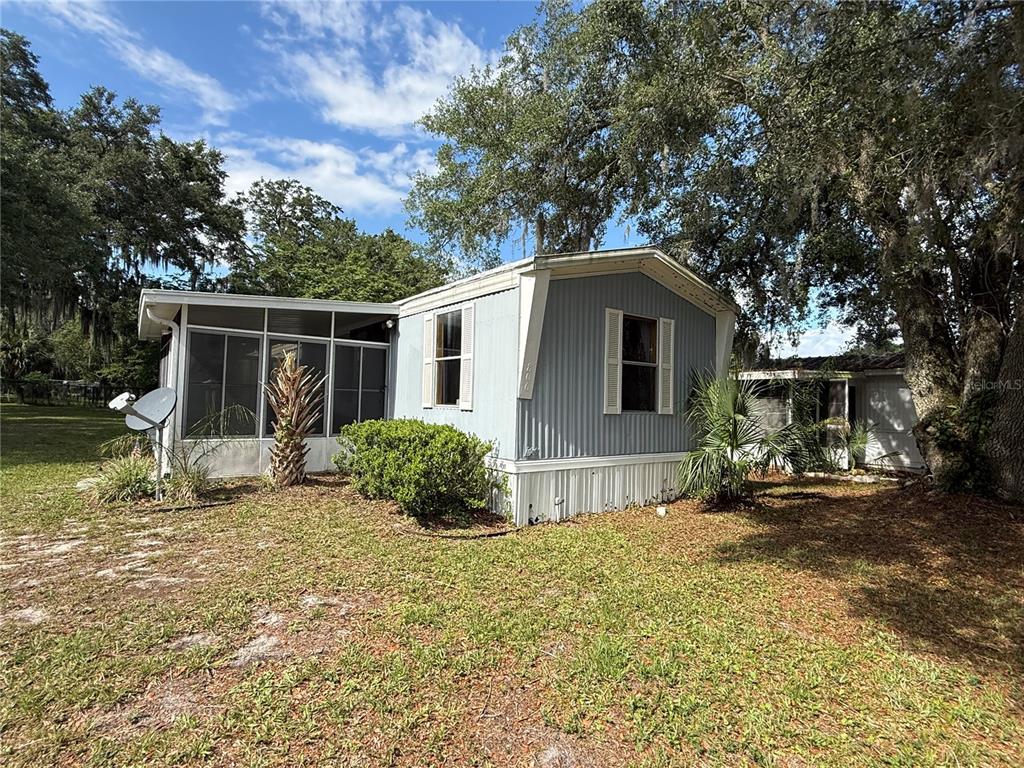 A light blue mobile home with a screened-in porch sits on a grassy lot — 806 NEW HAMPSHIRE AVENUE, WILDWOOD, FL