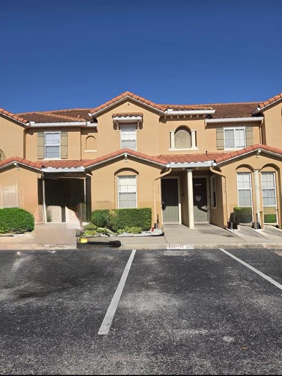 A two-story tan stucco townhouse with a tiled roof and two front entrances — 5520 PARADISE CAY CIRCLE, KISSIMMEE, FL
