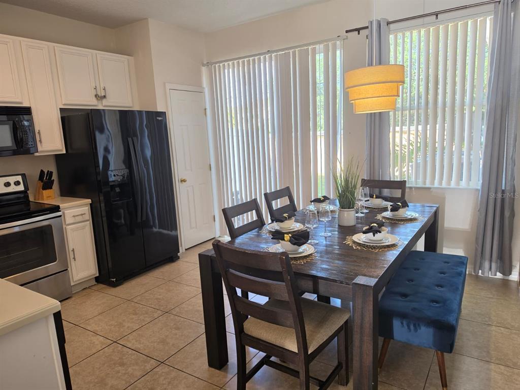 A kitchen and dining area featuring a dark wood table, black refrigerator, and tile flooring — 5520 PARADISE CAY CIRCLE, KISSIMMEE, FL