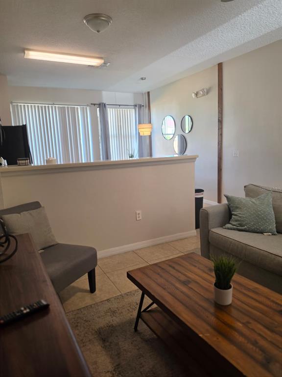 A living room features a low partition wall, tile flooring, and a wooden coffee table — 5520 PARADISE CAY CIRCLE, KISSIMMEE, FL