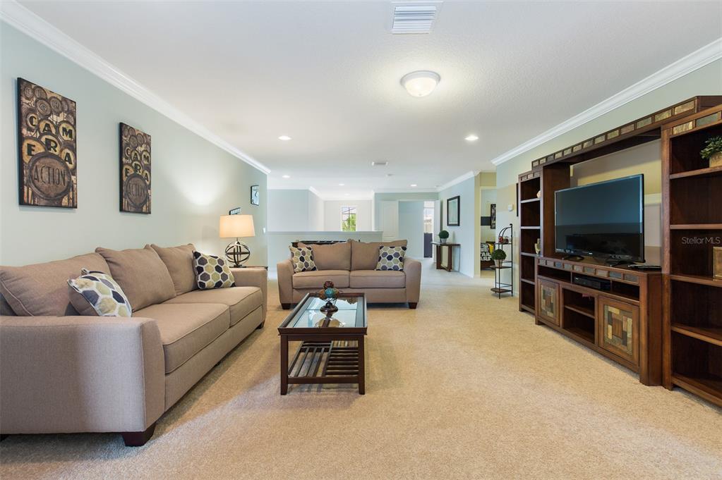 A living room features two beige sofas, a coffee table, and a large wooden entertainment center — 8801 RHODES STREET, KISSIMMEE, FL