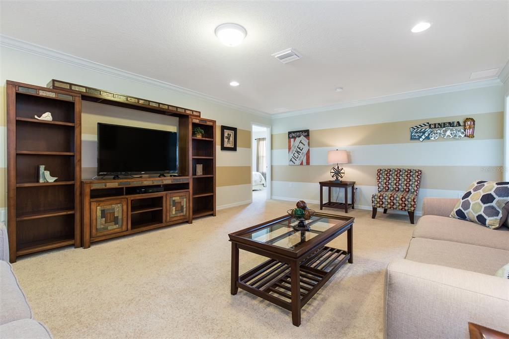 A living room features a large wooden entertainment center, a glass-topped coffee table, and striped walls — 8801 RHODES STREET, KISSIMMEE, FL