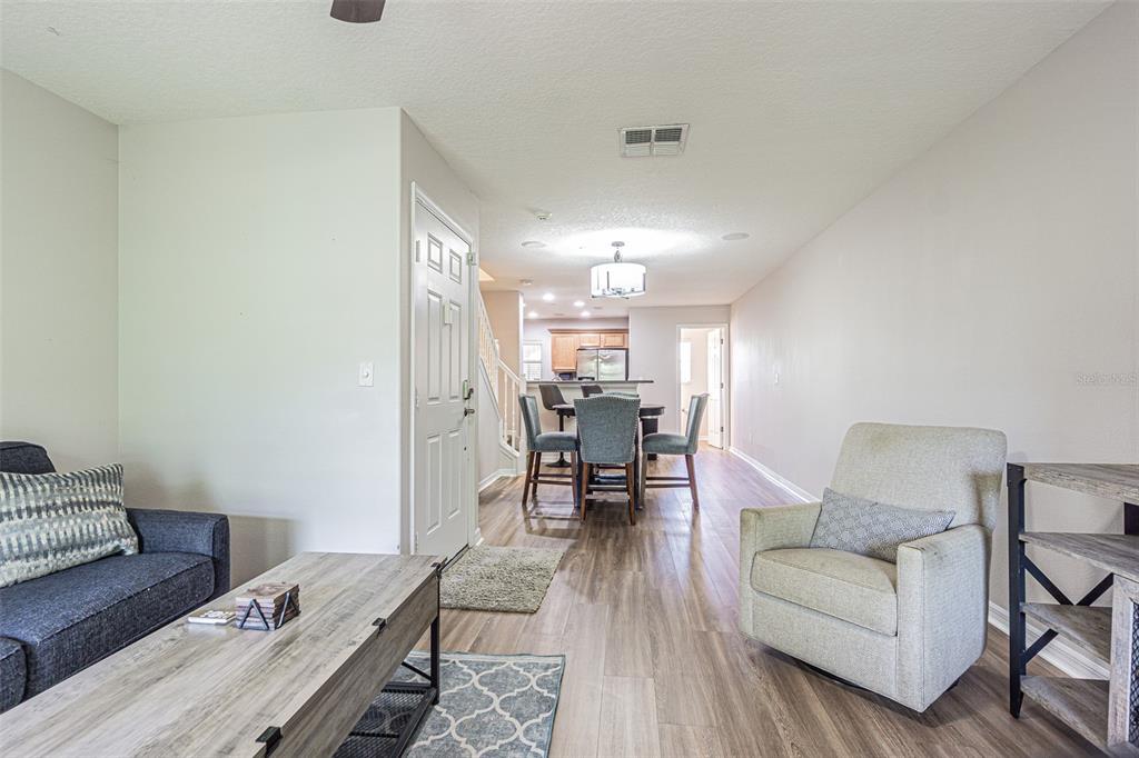 An open-concept living and dining area features wood-look flooring, a sofa, and a dining table — 526 WHEATON TRENT PLACE, TAMPA, FL