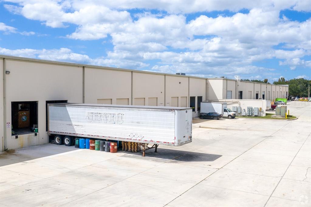 An exterior view of a commercial warehouse building with a semi-trailer parked at a loading dock — 4333 SILVER STAR ROAD UNIT 13, ORLANDO, FL