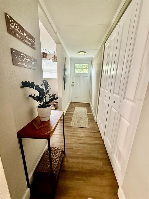 A hallway features wood-look flooring, a white front door, and a wooden console table — 217 KELLY STREET S, LAKE HAMILTON, FL