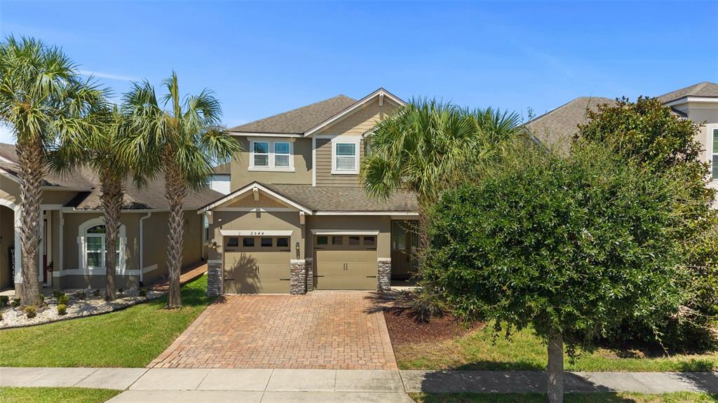 A two-story house with a tan exterior, two garage doors, and a brick driveway — 2544 FOLIO WAY, KISSIMMEE, FL