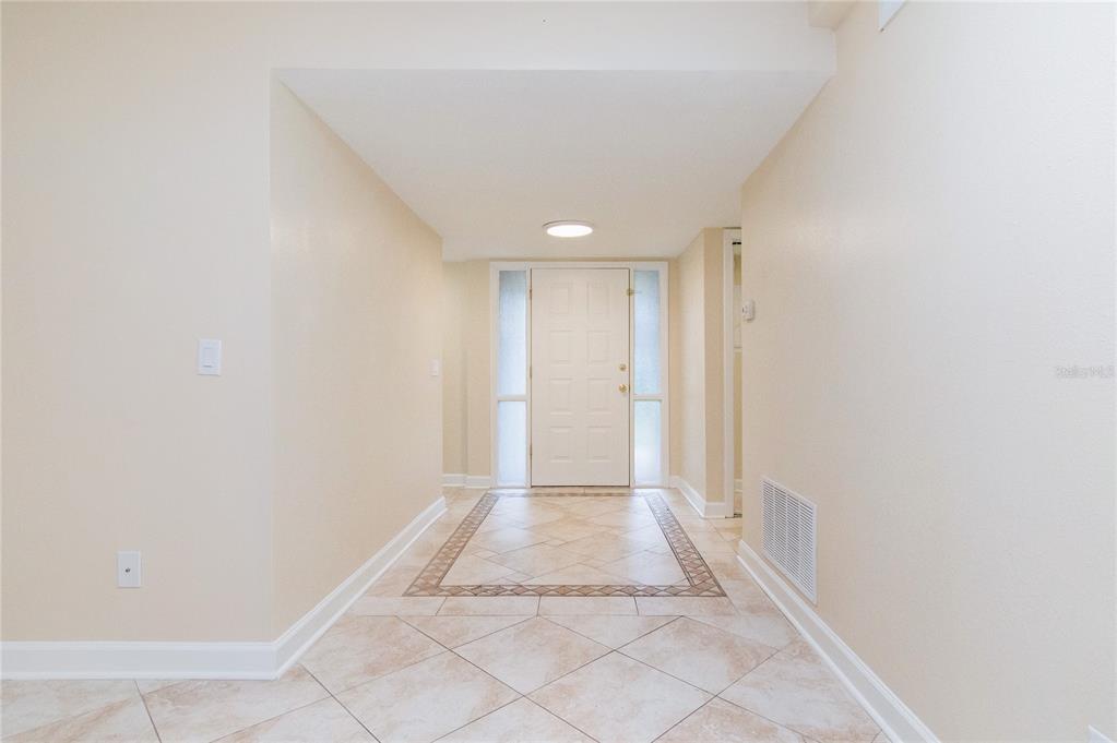 An entryway features a white front door with sidelights, tile flooring, and beige walls — 602 DESOTO DRIVE, CASSELBERRY, FL