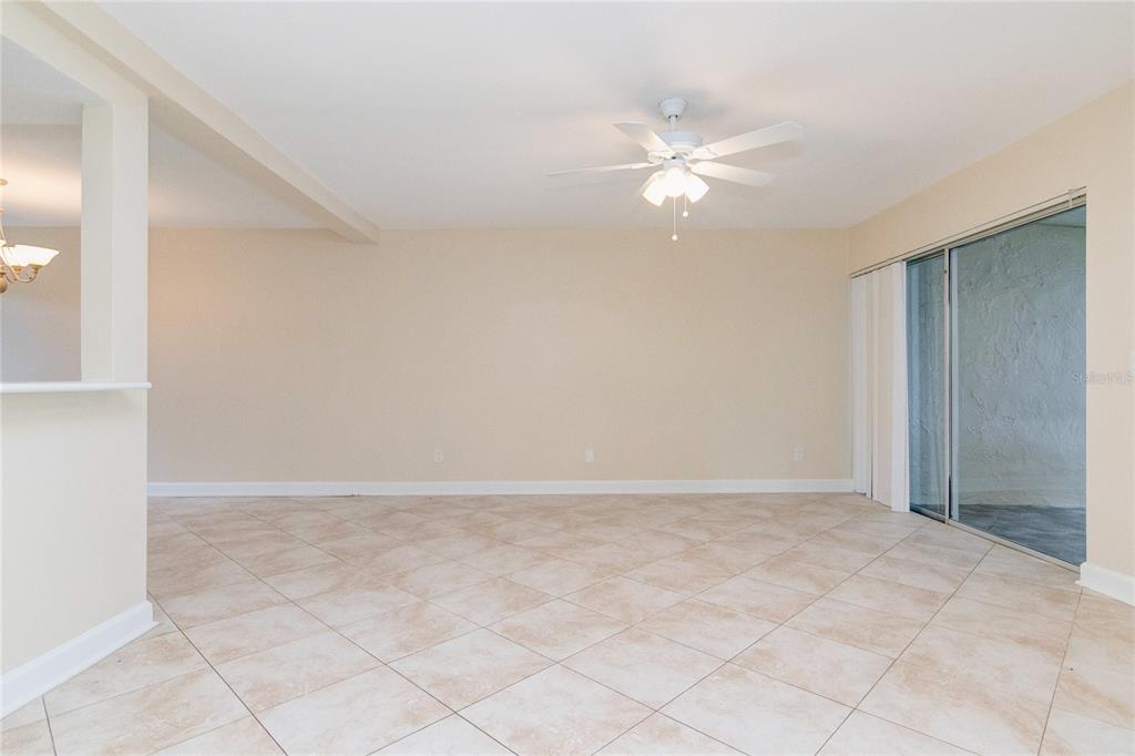 An empty living area features beige tile flooring, a ceiling fan, and sliding glass doors — 602 DESOTO DRIVE, CASSELBERRY, FL