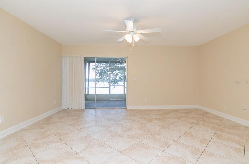 An empty room with beige walls, tile flooring, a ceiling fan, and sliding glass doors — 602 DESOTO DRIVE, CASSELBERRY, FL