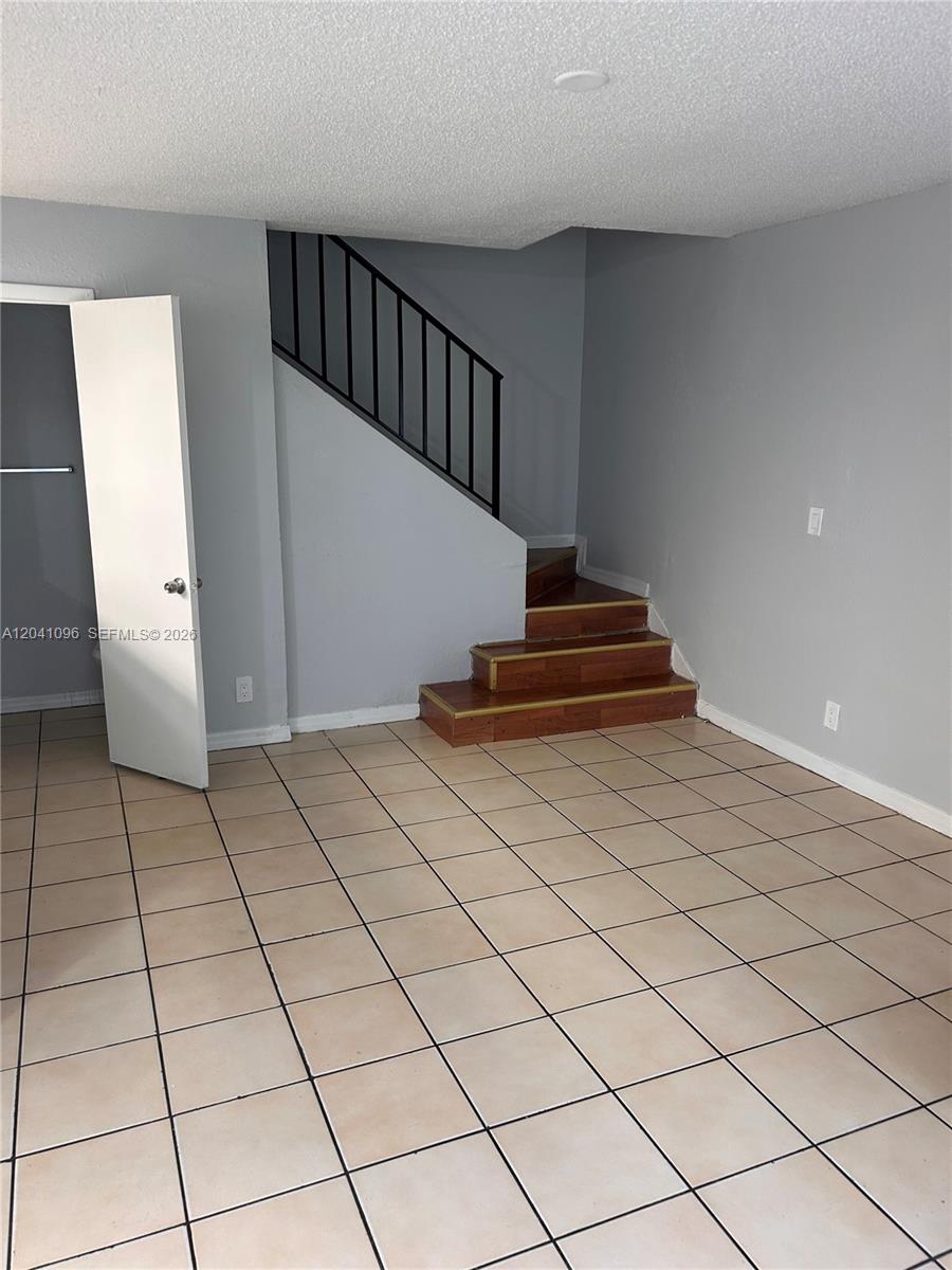 A room with light-colored tile flooring, gray walls, and a staircase with wooden steps — 2091 Ilene DR # 2, Delray Beach FL 33445, DELRAY BEACH, FL