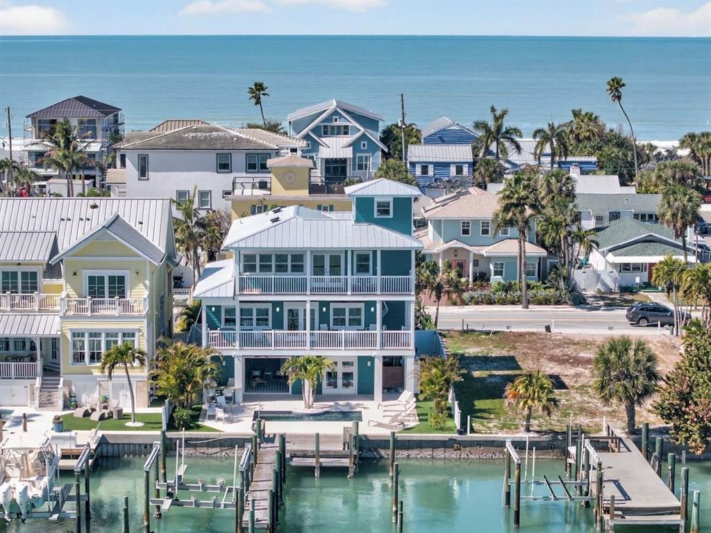 An aerial view of a multi-story teal house with balconies, a pool, and a private dock — 2503 PASS A GRILLE WAY, ST PETE BEACH, FL
