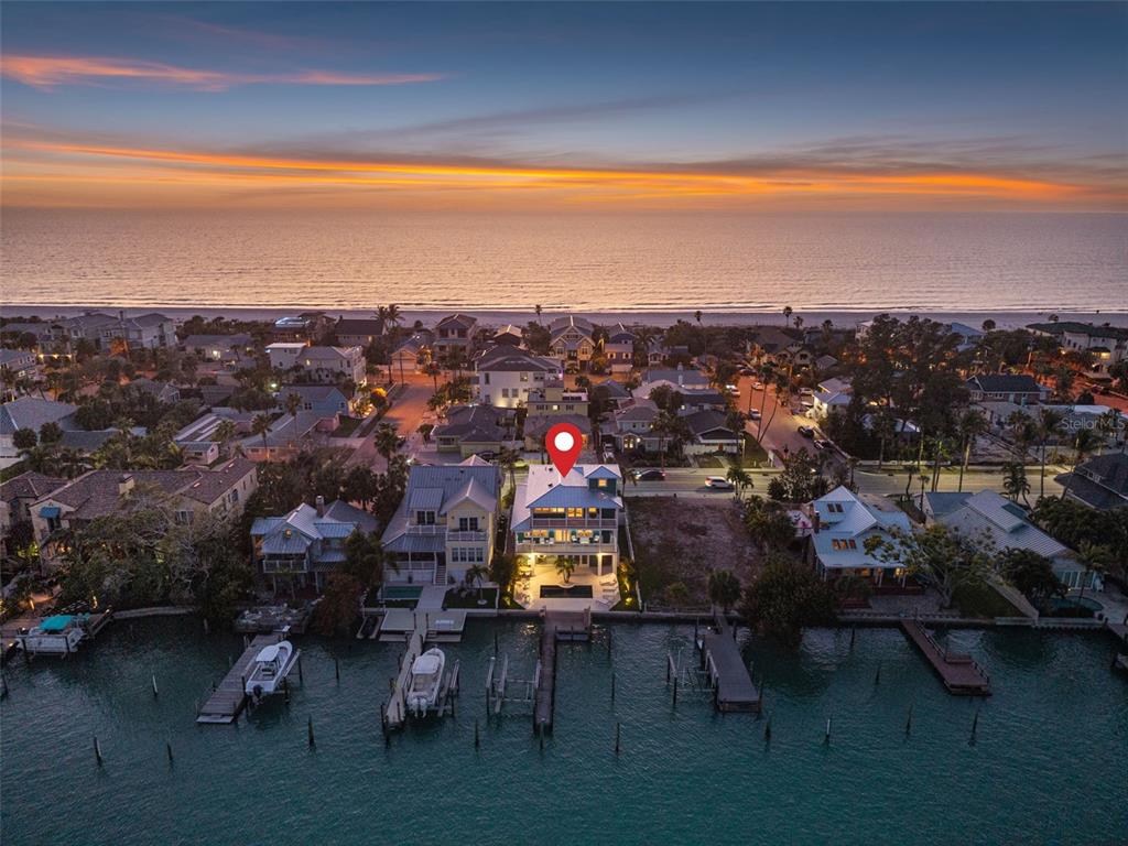 An aerial view shows a waterfront house with a pool and dock at sunset — 2503 PASS A GRILLE WAY, ST PETE BEACH, FL