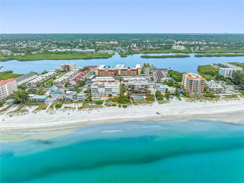 An aerial view of a sandy beach, turquoise water, and several multi-story residential buildings — 19701 GULF BOULEVARD UNIT 307, INDIAN SHORES, FL