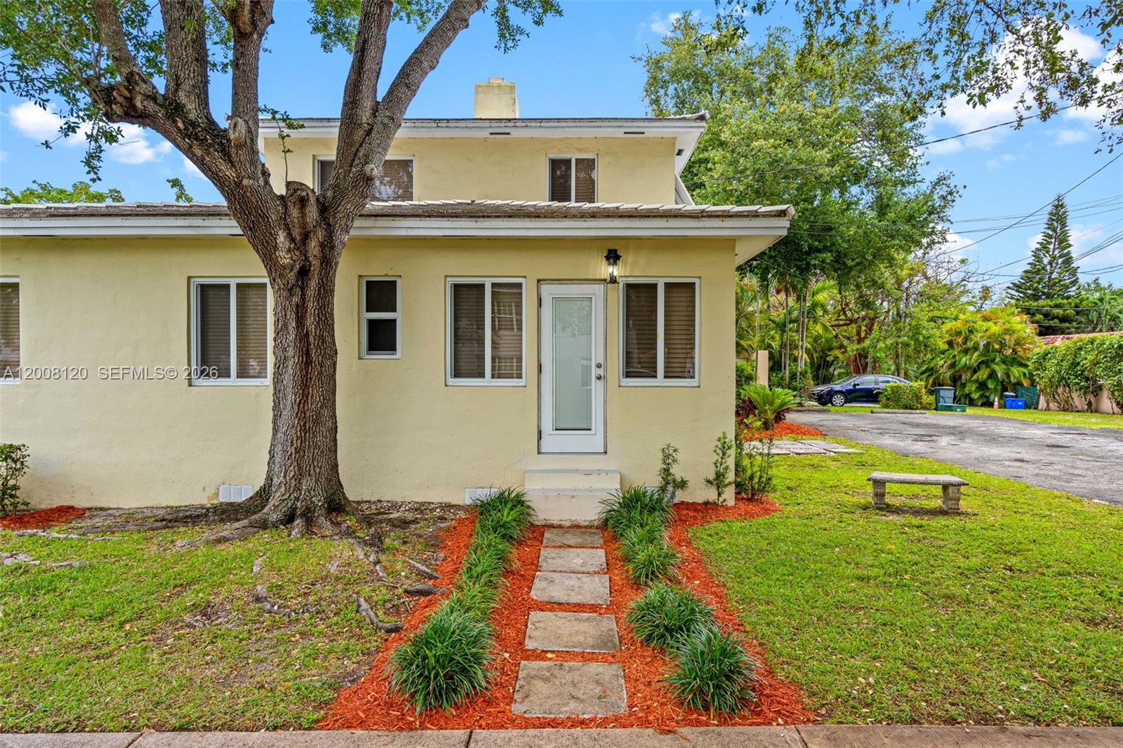 A two-story yellow house features a stone walkway leading to a white front door — 3500 Ponce De Leon Blvd, Coral Gables FL 33134, CORAL GABLES, FL