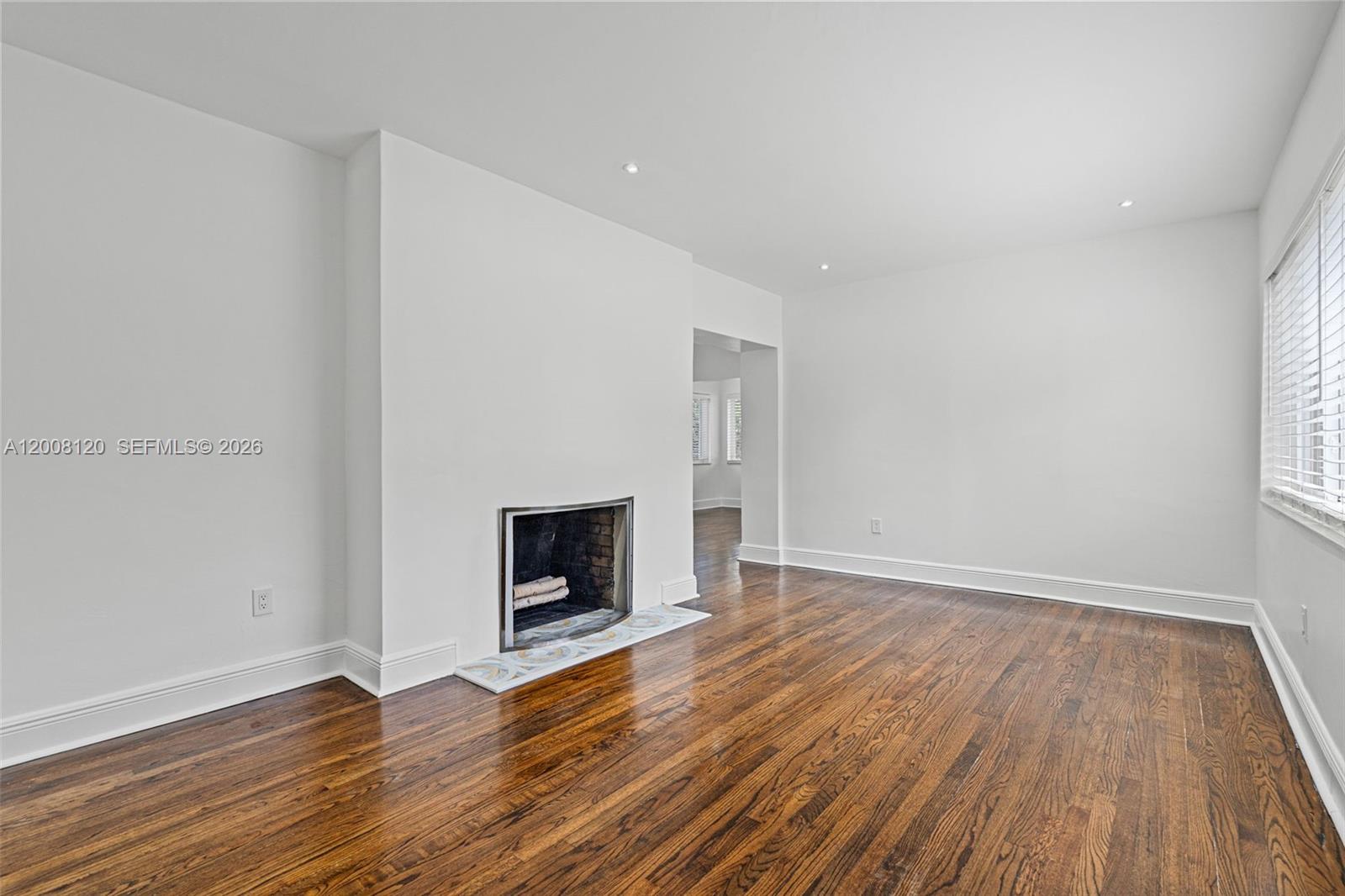 A room with hardwood floors, white walls, and a fireplace with a tiled hearth — 3500 Ponce De Leon Blvd, Coral Gables FL 33134, CORAL GABLES, FL