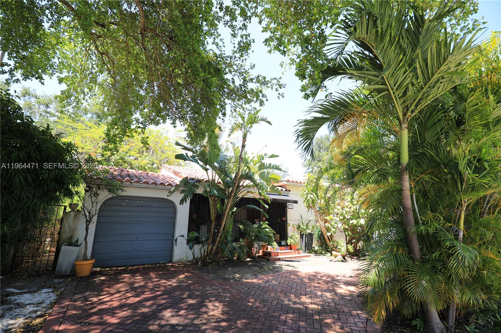 A single-story house with a garage, brick driveway, and lush tropical landscaping — 655 NE 82nd St, Miami FL 33138, MIAMI, FL