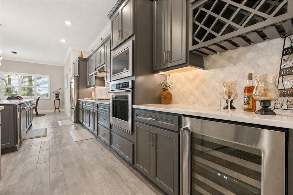 A kitchen features dark gray cabinetry, stainless steel appliances, a wine cooler, and tile flooring — 15351 WILLOW RIDGE DRIVE, MONTVERDE, FL