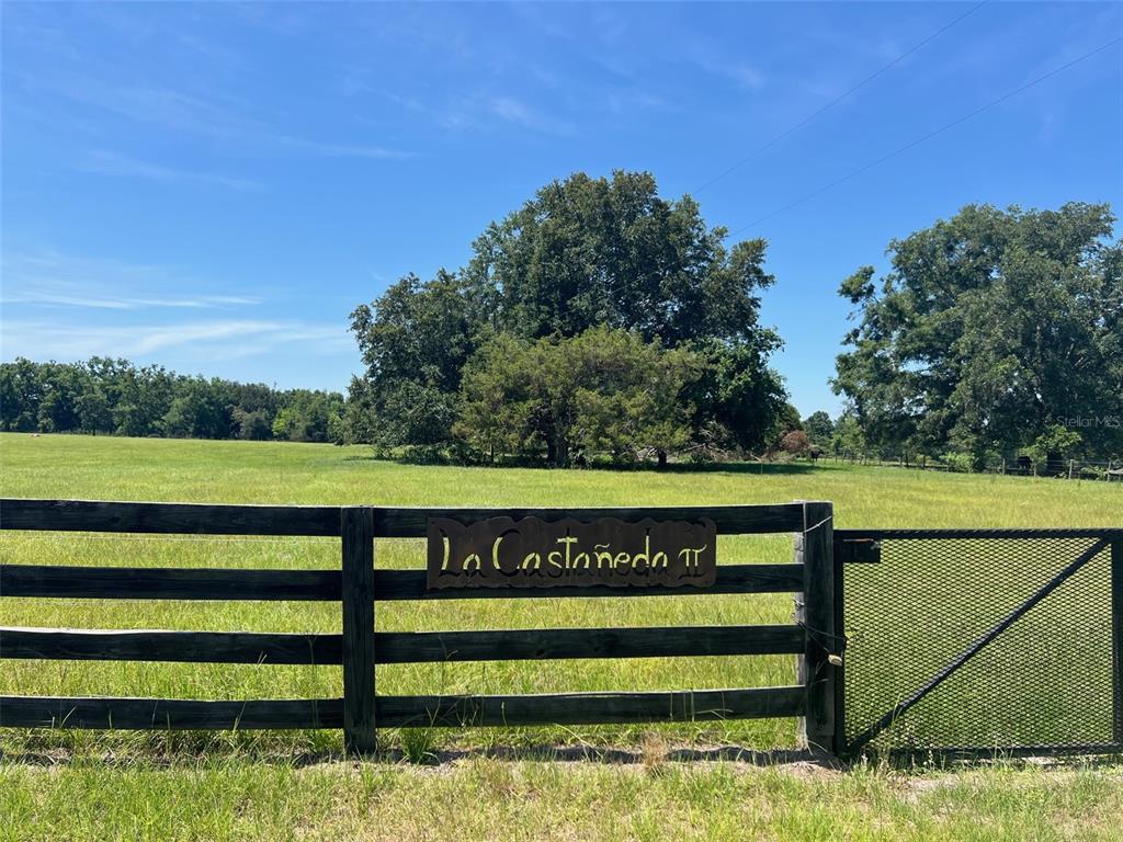 A wooden fence with a metal sign reading La Castañeda borders a large grassy field — 00 NW 165TH AVENUE, HIGH SPRINGS, FL
