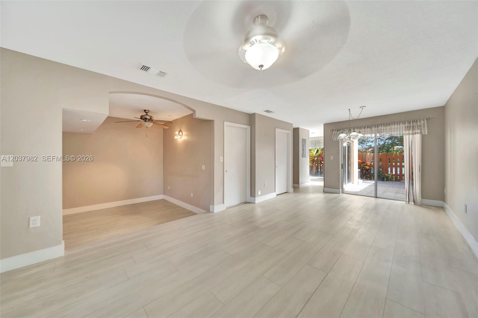 A living area with light wood-look flooring, ceiling fans, and sliding glass doors to a patio — 3773 SW 153rd Ct # 3773, Miami FL 33185, MIAMI, FL