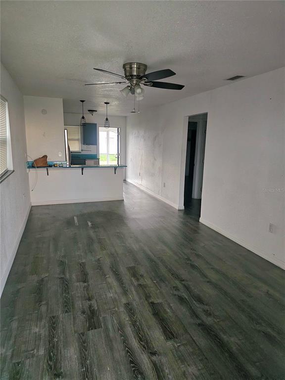 An open-concept living area features wood-look flooring, a ceiling fan, and a kitchen breakfast bar — 1167 MEMORIAL DRIVE, AVON PARK, FL