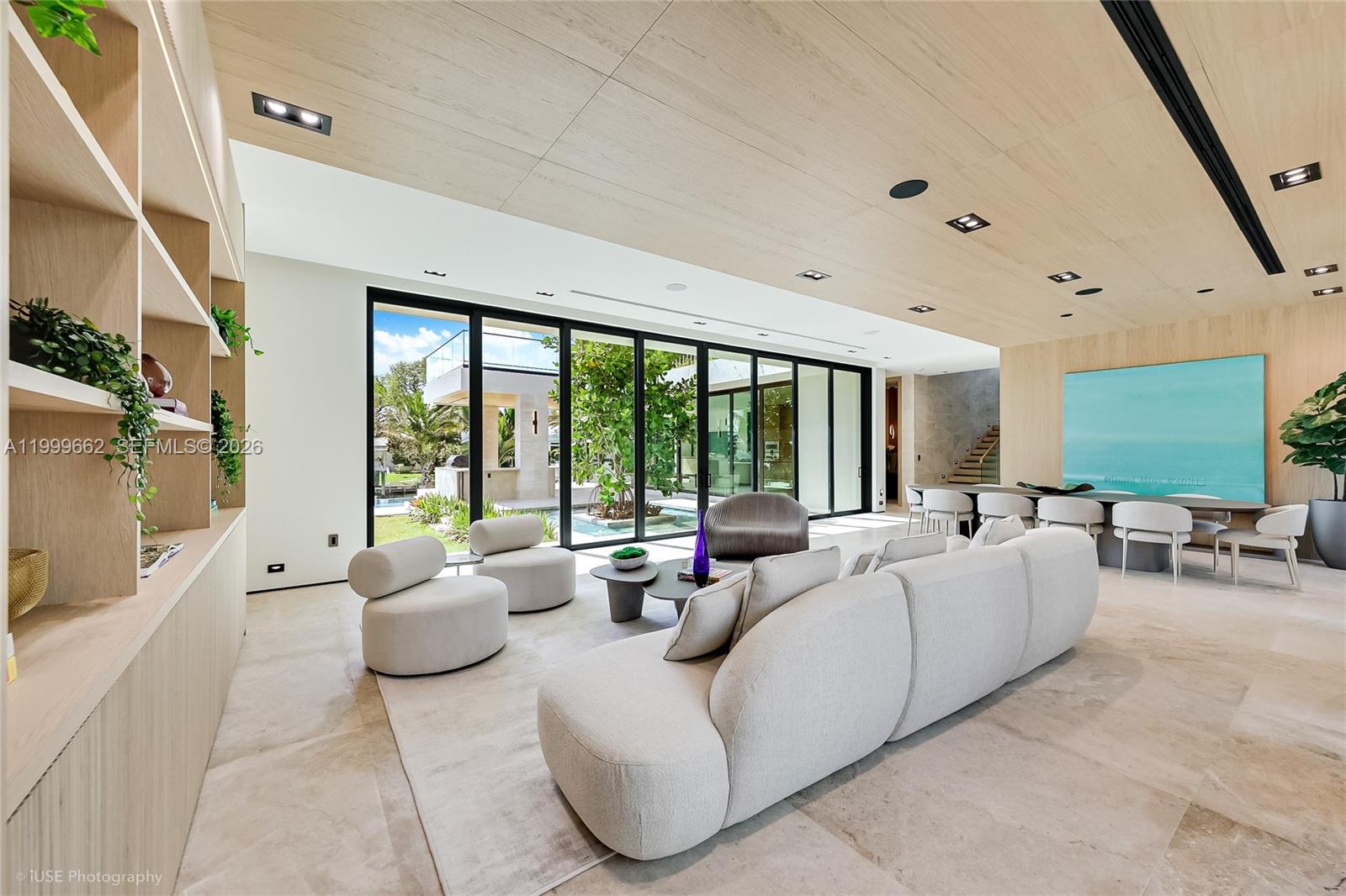 A modern living room features light wood paneling, a large sectional sofa, and floor-to-ceiling windows — 770 Lake Rd, Miami FL 33137, MIAMI, FL