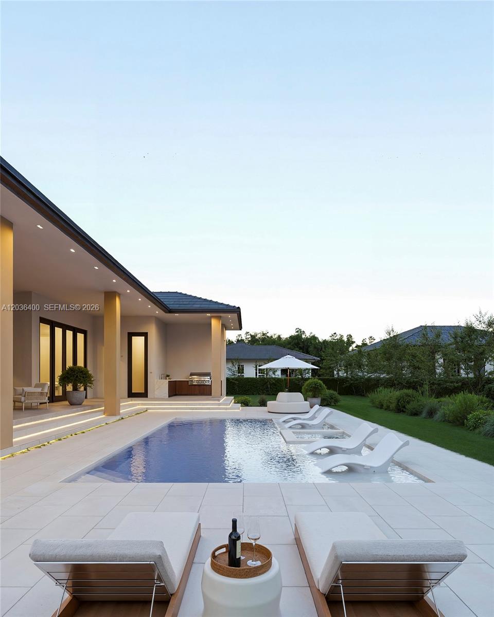A modern house exterior features a swimming pool with lounge chairs and a covered patio — 12720 SW 188 ST, Miami FL 33177, MIAMI, FL
