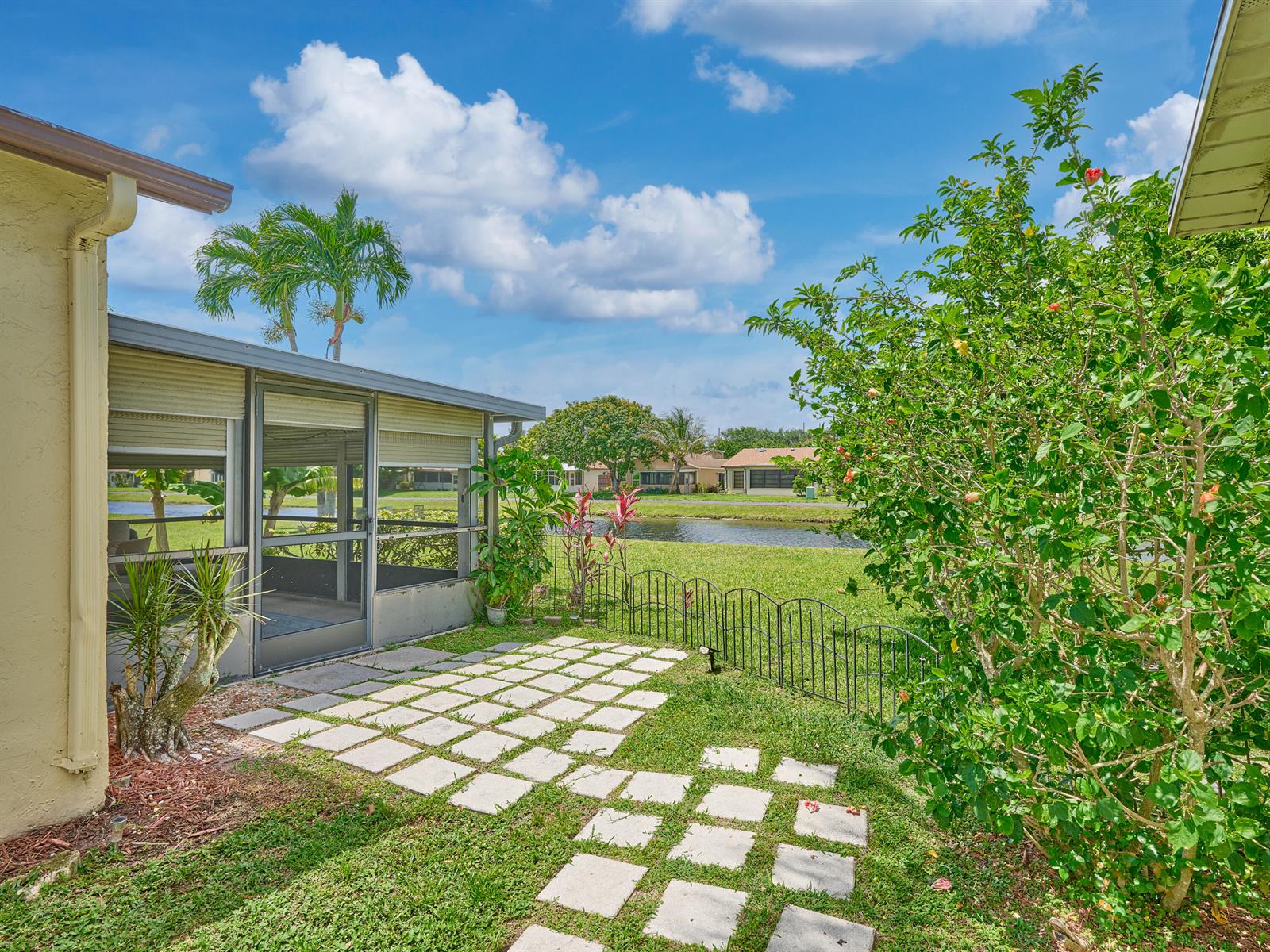A backyard patio with stone pavers, a screened-in porch, and a view of a canal — 5197 Minto Road, Boynton Beach FL 33472, BOYNTON BEACH, FL