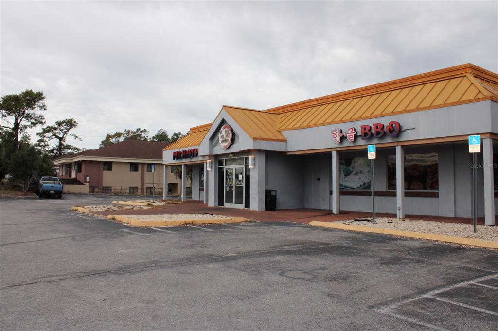 An exterior view of a commercial building with a tan roof and gray walls — 5399 COMMERCIAL WAY, SPRING HILL, FL