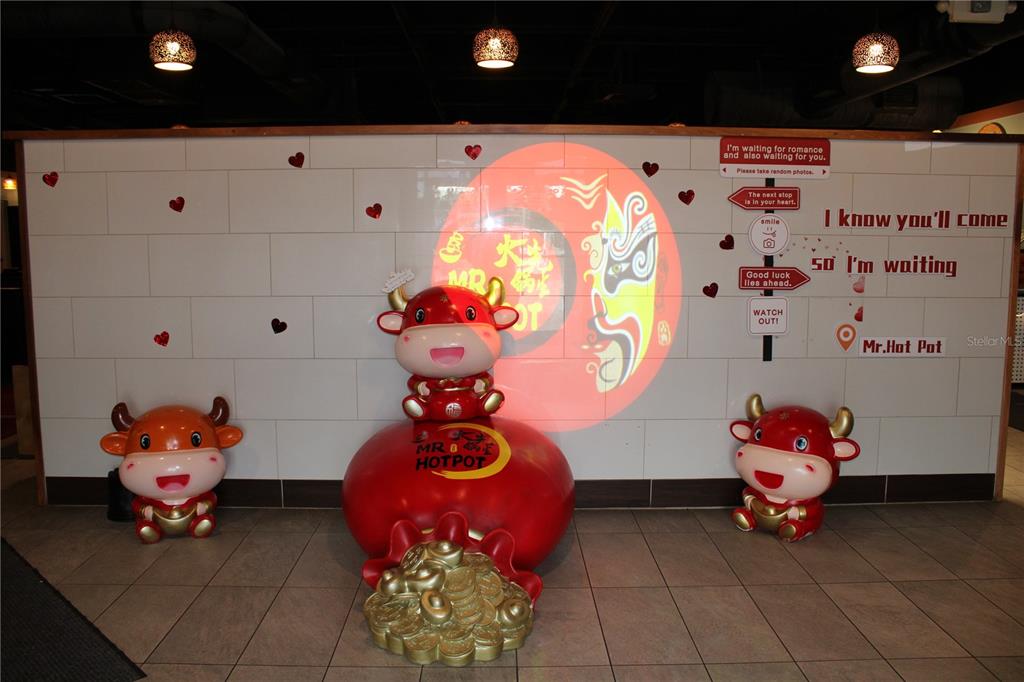 A restaurant interior features three cartoon bull statues and a wall with decorative signage — 5399 COMMERCIAL WAY, SPRING HILL, FL