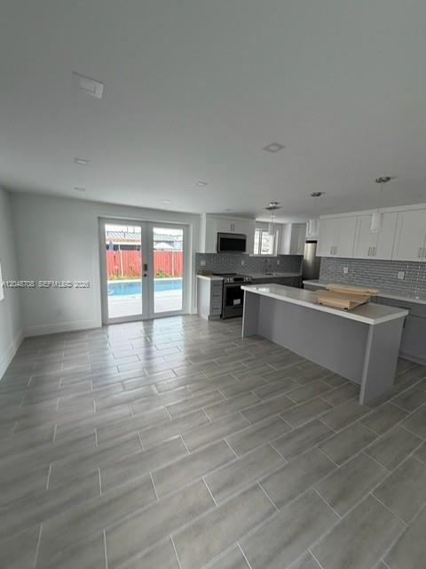 A modern kitchen and dining area features gray tile flooring, white cabinetry, and glass doors — 3515-3517 SW 91st Ave, Miami FL 33165, MIAMI, FL