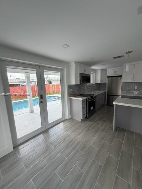 A kitchen with gray tile flooring, white cabinets, and glass doors opening to a pool — 3515-3517 SW 91st Ave, Miami FL 33165, MIAMI, FL