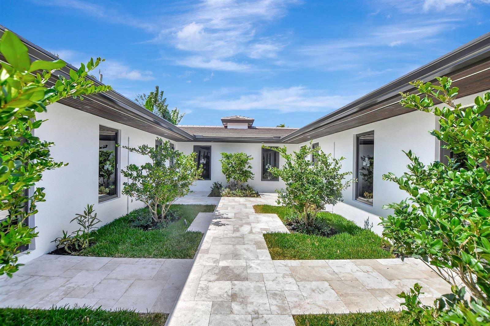 A modern courtyard features a stone walkway flanked by green lawns and small trees — 1361 SE 4th Street # 3, Deerfield Beach FL 33441, DEERFIELD BEACH, FL