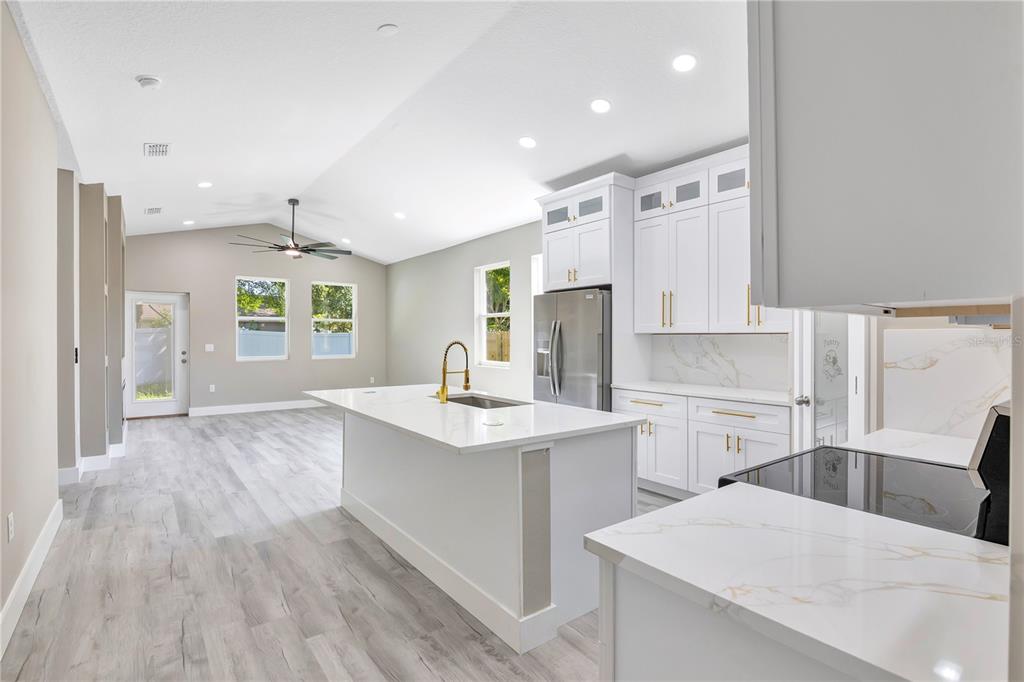 A modern kitchen features white cabinets, a large island with a sink, and light flooring — 231 E LAFAYETTE STREET, WINTER GARDEN, FL