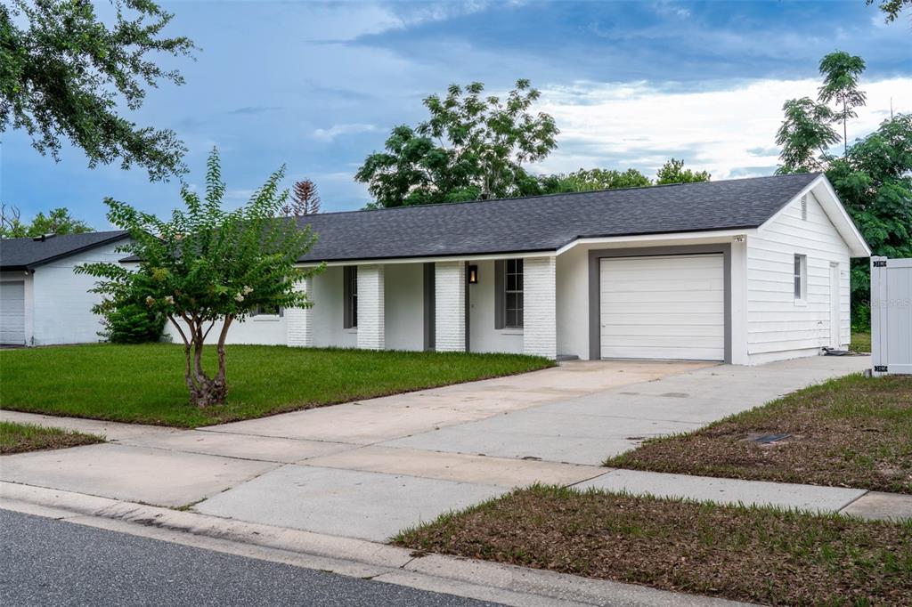 A white, single-story house with a dark shingled roof, attached garage, and front porch — 377 JEFFERSON DRIVE, CASSELBERRY, FL