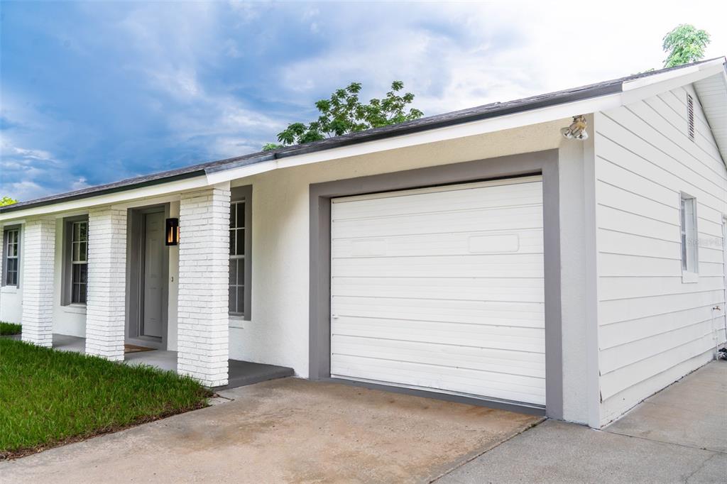 A white house exterior features a single-car garage, a covered entryway, and brick columns — 377 JEFFERSON DRIVE, CASSELBERRY, FL